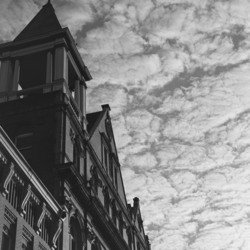 A building in front of a sky full of fluffy clouds